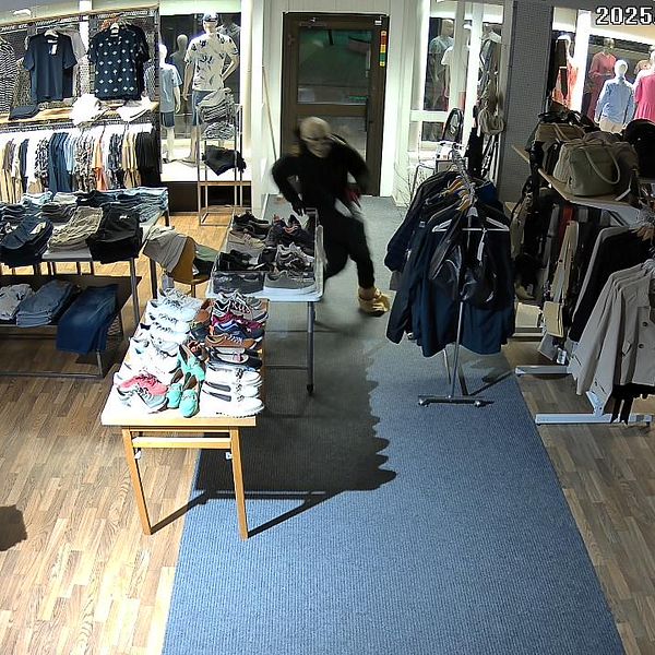 Bild från övervakningskamera som visar tjuv med dödskallemask inne i en butik.