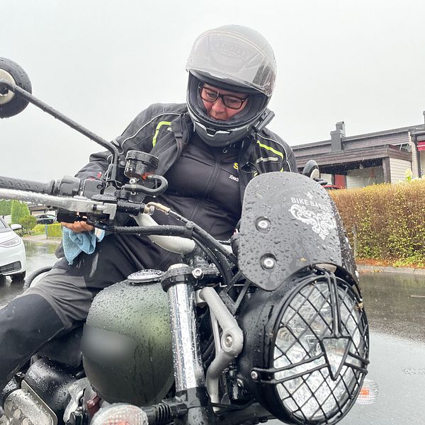 En kvinna på motorcykel med hjälm.