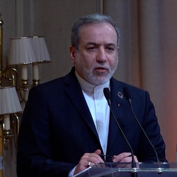 Abbas Araghchi talar vid ett podium med Irans flagga i bakgrunden.