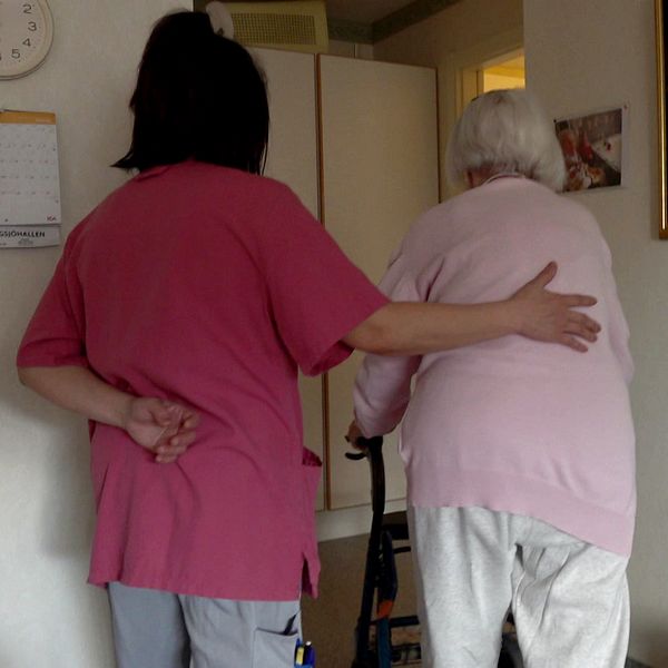 Vårdpersonal hjälper en äldre person.
