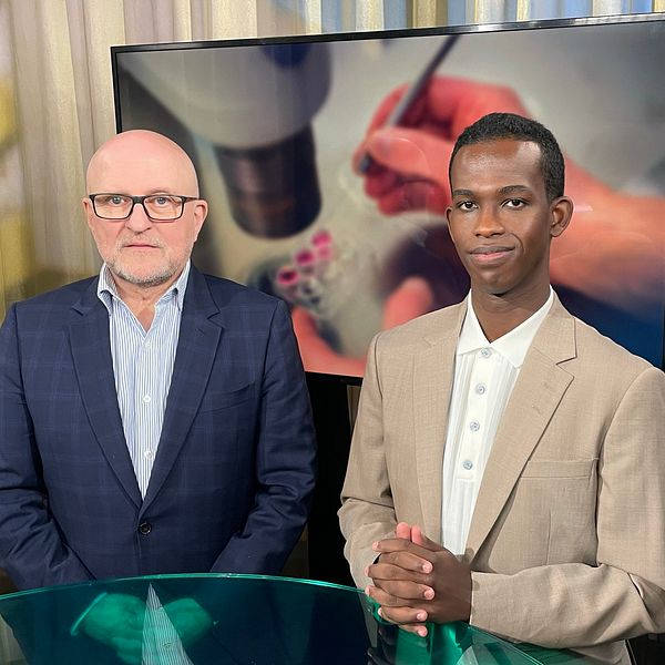 Till vänster, Sven-Eric Söder i en mörkblå kavaj med uppknäppt skjorta. Han har ett allvarligt ansiktsuttryck. Till höger programledaren Abdi Mohamed som tittar in i kameran med ett litet leende.