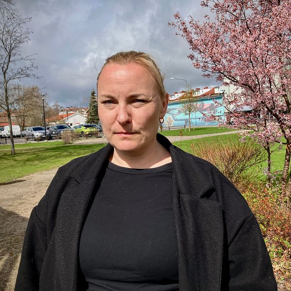 Sophie Dahlberg (V) i svart jacka står utomhus, med blommande träd och hus i bakgrunden.