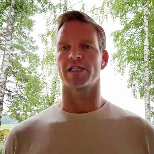 Riku Tapio talar framför fönster med grönskande träd utanför