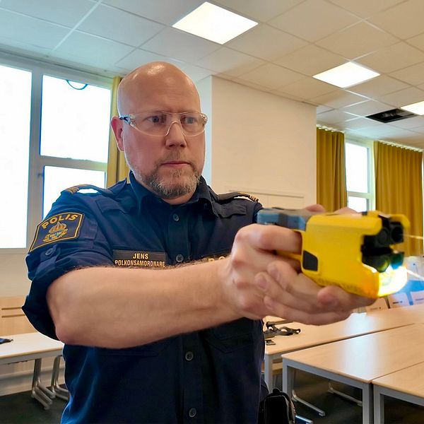 En polis håller det nya elchockvapnet framför sig.