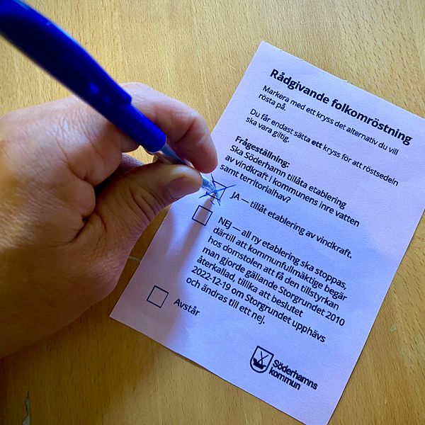 Röstsedel och en hand som kryssar Ja