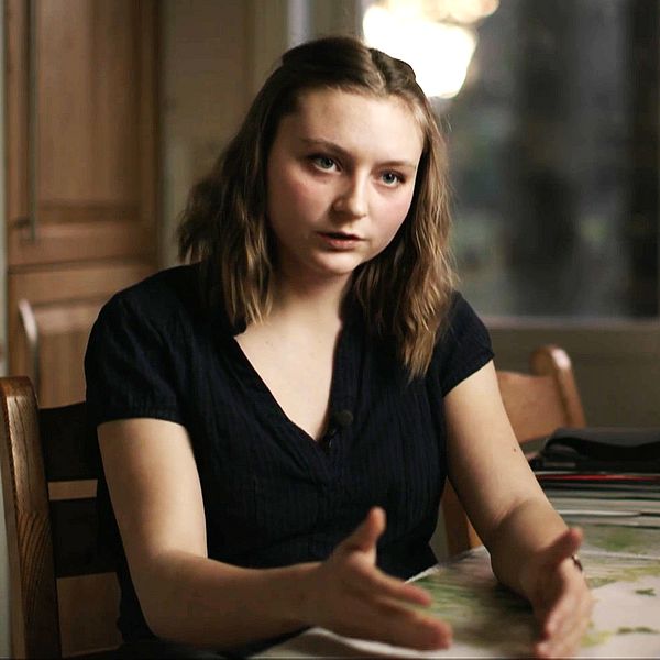 En ung kvinna intervjuas vid ett köksbord.