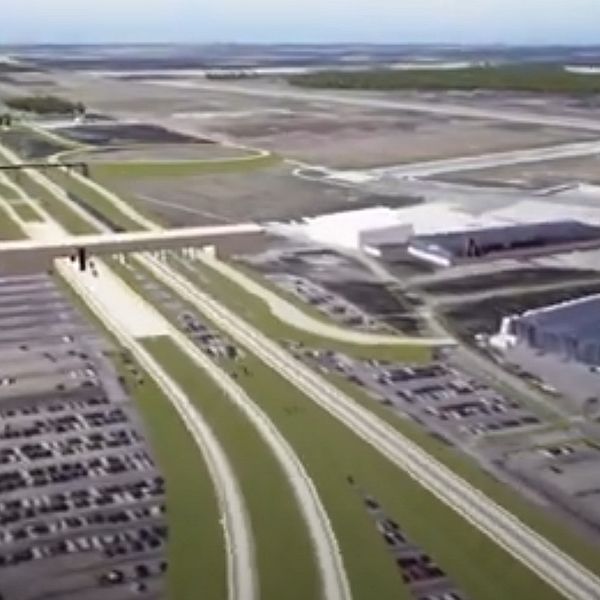Flygbild över en stor industrikomplex med parkeringsplats och omgivande vägar.
