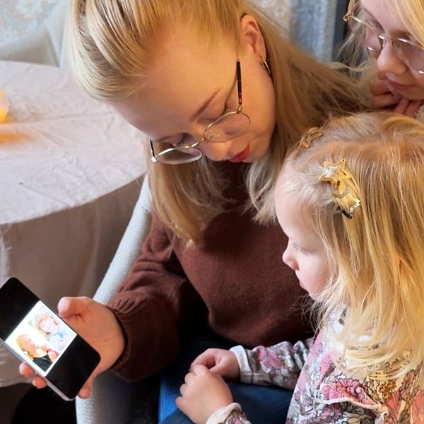 Michaela Stolpe och lilla Selma tittar tillsammans på en mobiltelefon.