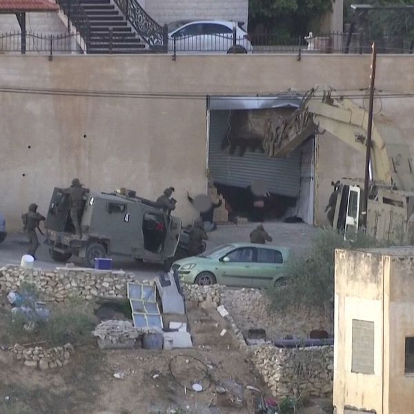 Två män överlämnar sig med uppsträckta händer till israeliska soldater i Jenin.