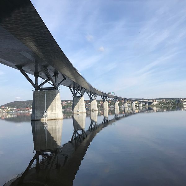 Sundsvallsbron sett underifrån en vacker sommardag. Vattnet ligger spegelblankt över sundsvallsfjärden