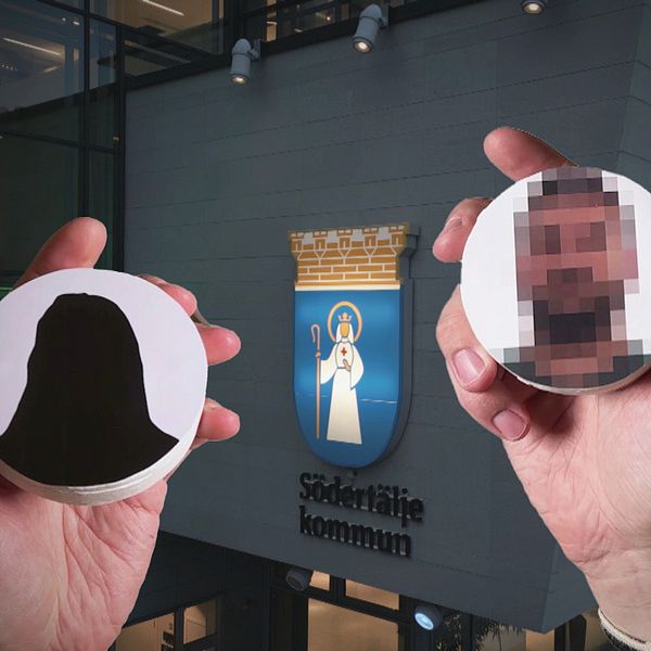 Två händer håller runda skyltar framför Södertäljes kommuns byggnad.