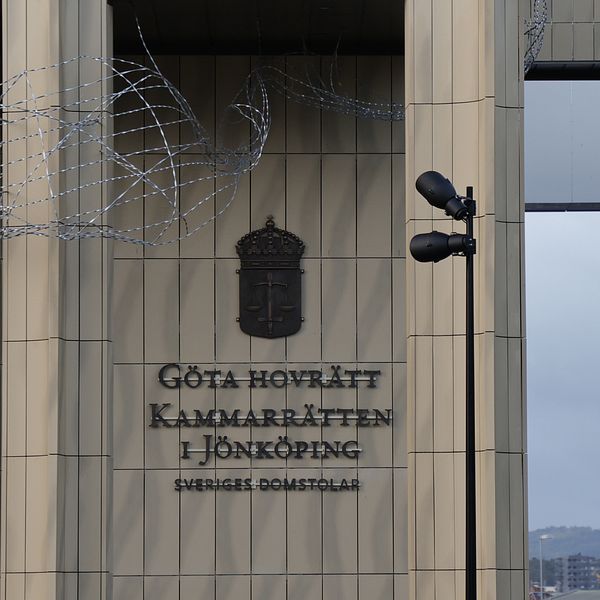 Fasaden av Göta hovrätt i Jönköping med synlig logotyp och text på byggnaden som lyder ”Kammarrätten i Jönköping, Sveriges Domstolar”, omgiven av taggtråd och övervakningskameror.