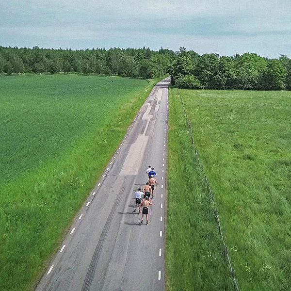 Skidlandslaget tränar med rullskidor på en tom landsväg. Drönarbild.