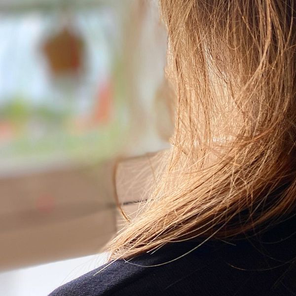Kvinna i mört hår sitter med ryggen vänd