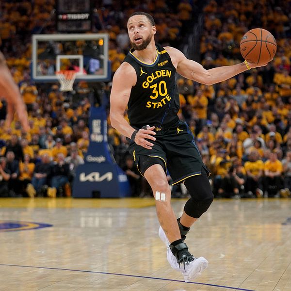 Basketspelaren Stephen Curry driver bollen under match inför publik på fullsatt arena.