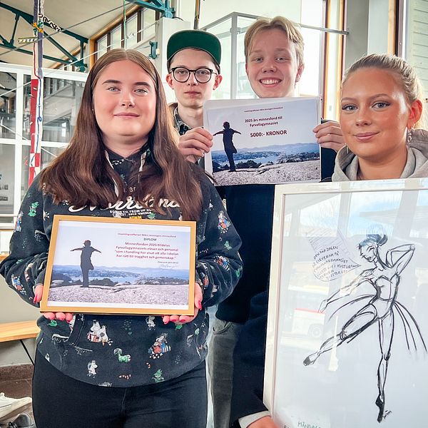 Fyra personer visar upp teckningar och tavlor med dansmotiv inomhus.