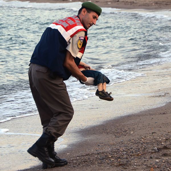 En turkisk militärpolis bär bort den döda pojken.