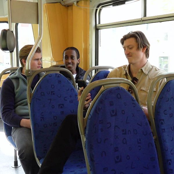Tre personer sitter på säten i en spårvagn.