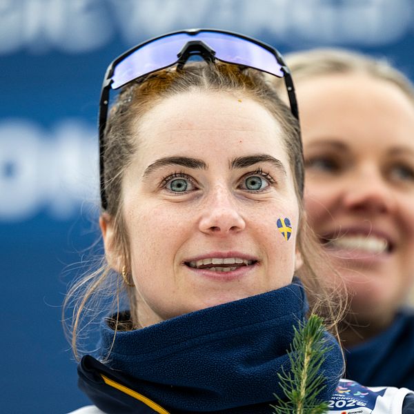 En person med sportglasögon är med i ett evenemang, omgiven av blå bakgrund med text.