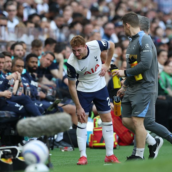 En Tottenhamspelare håller sig för höften och får hjälp vid sidlinjen under en match.