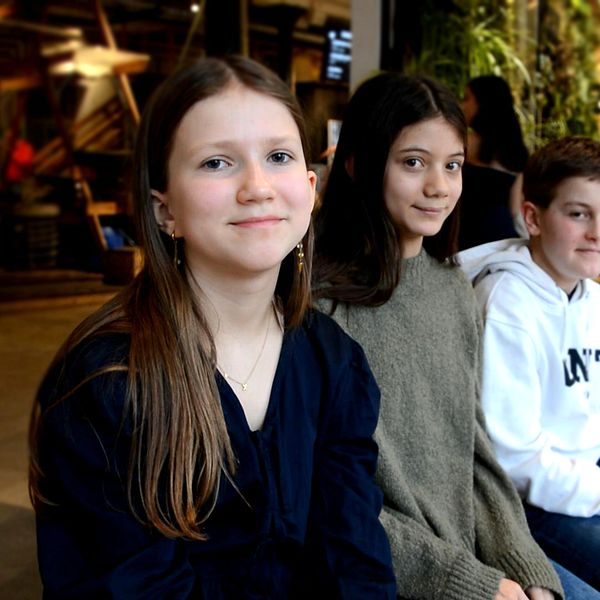 Tre skolelever personer sitter vid ett bord i en livlig inomhusmiljö, inne på Tom tits experiment i Södertälje.