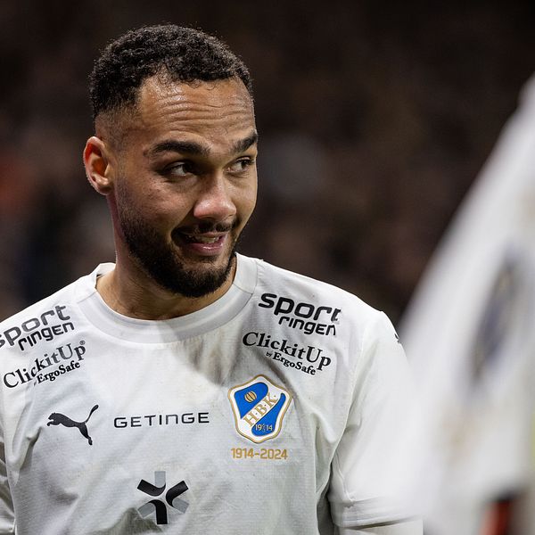 Fotbollsspelare i vit uniform vid hörnflagga på planen.