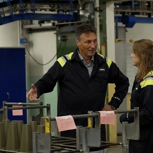 En man pratar med en kvinna i en fabriksmiljö