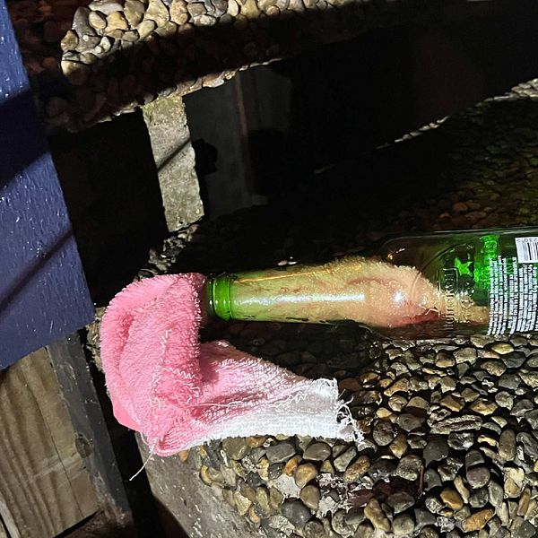 Bild på en av flaskorna som hittades vid adressen. En grön glasflaska med en rosa trasa som sticker ut ur flaskhalsen.