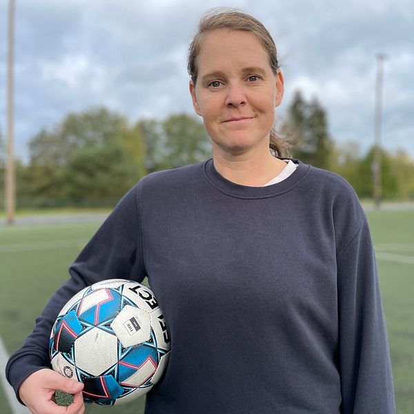 Biträdande universitetslektor Emma Lindkvist på fotbollsplan hållandes boll