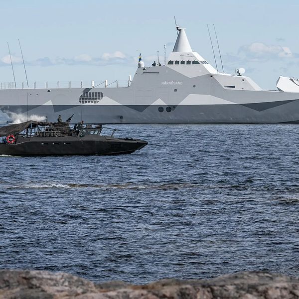 Svenskt örlogsfartyg i Östersjön med en mindre båt i förgrunden