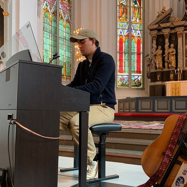 Före detta idoldeltagaren Luka Nemorin sitter vid ett piano och spelar i en kyrka i Kristinehamn