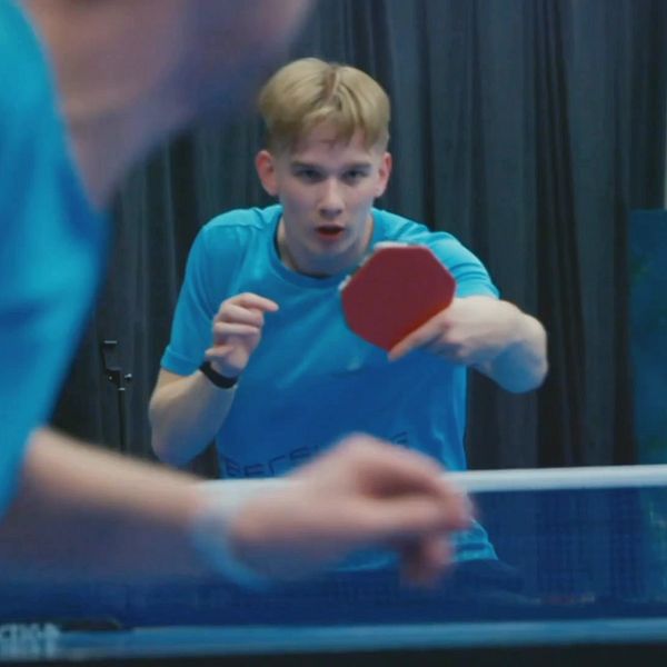 Alex spelar bordtennis under en match inomhus.