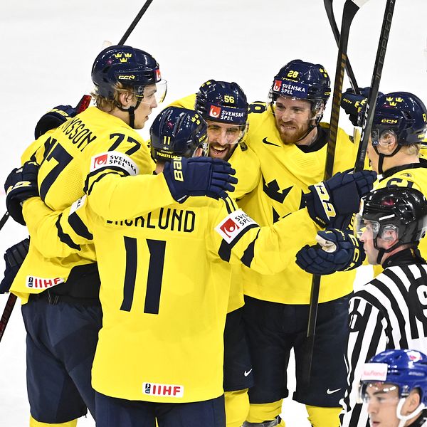 Svenska ishockeyspelare i gula tröjor firar mål mot ett lag i blå och röd utrustning.