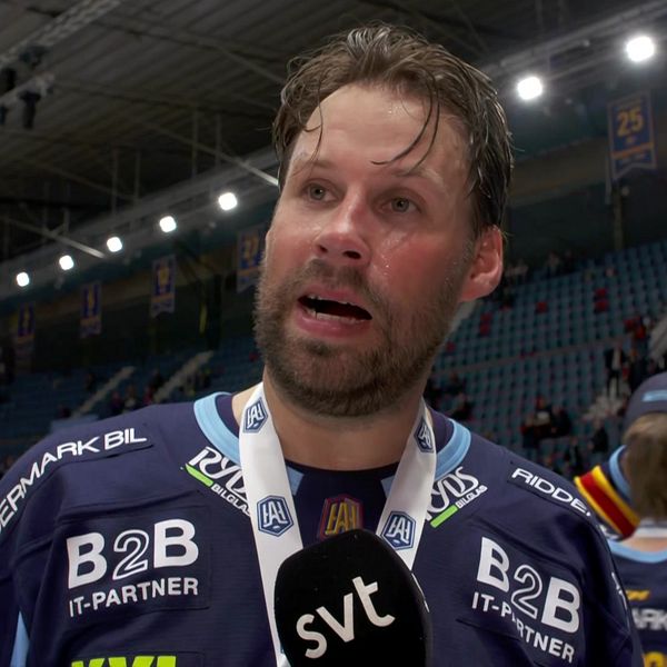 Ishockeyspelare intervjuas av SVT efter match, med medalj runt halsen i fullsatt arena.