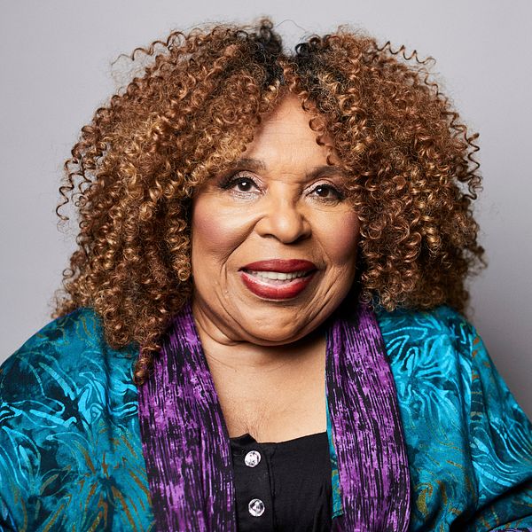 Roberta Flack i färgglad klädsel framför en grå bakgrund.