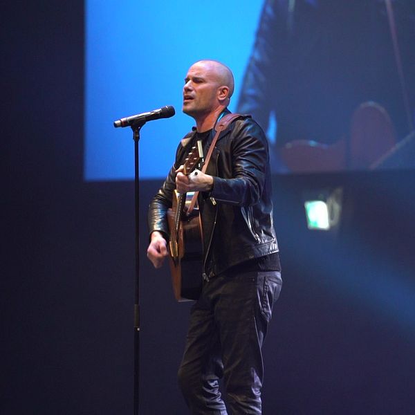 Man med gitarr sjunger på scen under ett framträdande på idrottsgalan i Örebro.