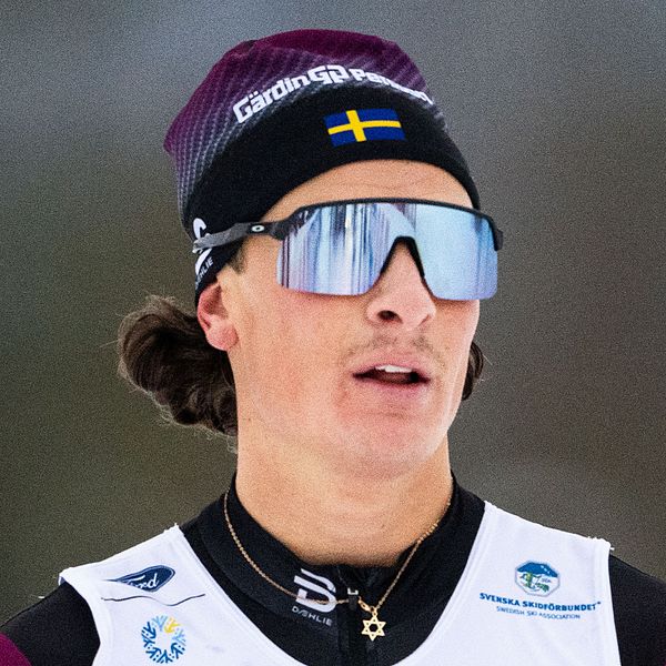 Skidåkare med svensk flagga på pannbandet, vintermiljö.