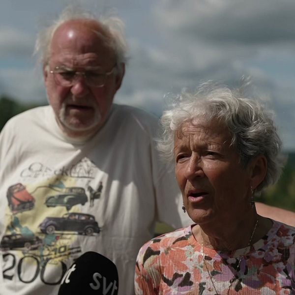 Två äldre personer står utomhus med en SVT-mikrofon framför sig.