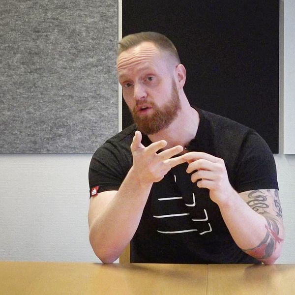 Tage Norén från Frivåden i Eskilstuna, kortklippt man i svart t-shirt, sitter ned vid skrivbord och pratar om hur de jobbar med kriminella ungdomar