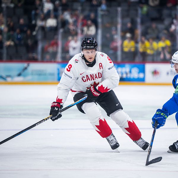 Ishockeymatch mellan Kanada och Slovenien, två spelare kämpar om pucken på isen.
