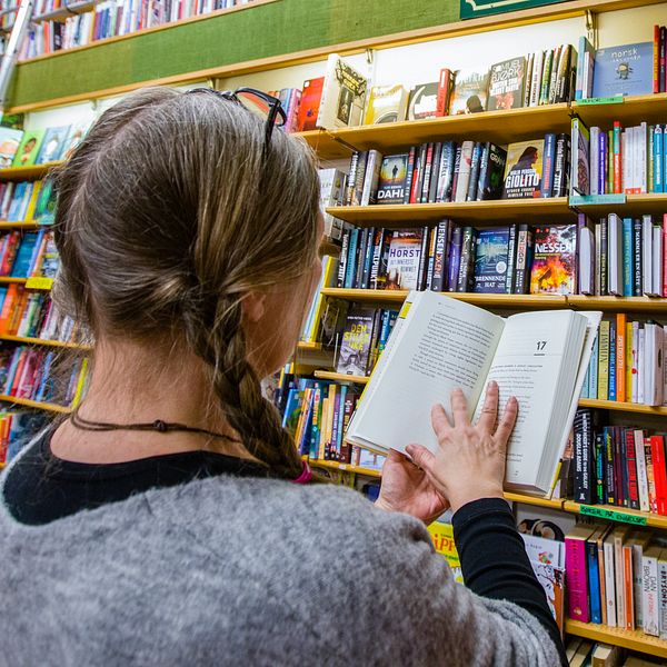 Kvinna i bokhandel läser bok.