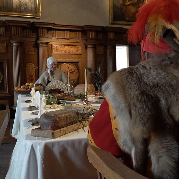 En man och en kvinna sitter vid ett bord och visar hur ett julfirande på Kalmar slott 1500-tal kunde se ut.