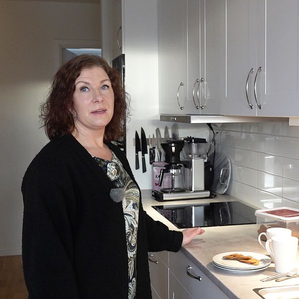 På bilden syns Marianne Kjellberg som står i familjens kök. Hon tittar mot kameran och har ena handen på köksbänken där det står tallrikar, pepparkakor och muggar.
