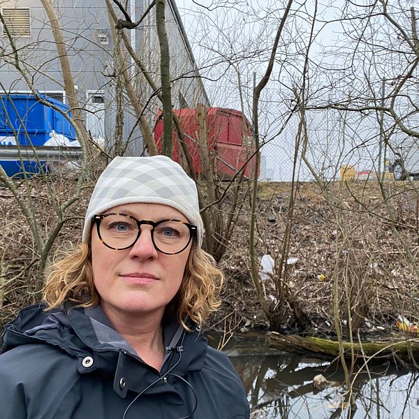 Katarina Ås står framför en skräpfylld bakgrund vid Rocksjöns naturreservat.