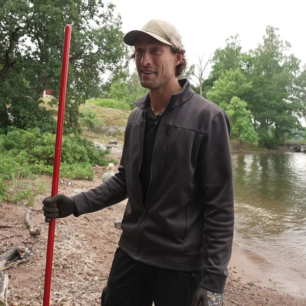 Christoffer städar bort skräp från stranden.