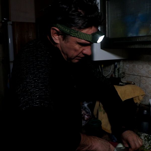 Oleh Kobetskij lagar mat i en mörk lägenhet med en pannlampa på huvudet