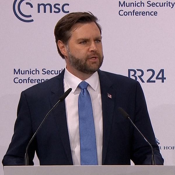 En man iklädd kostym står vid ett podium på München säkerhetskonferens, med logotyper för MSC och BR24 synliga i bakgrunden.