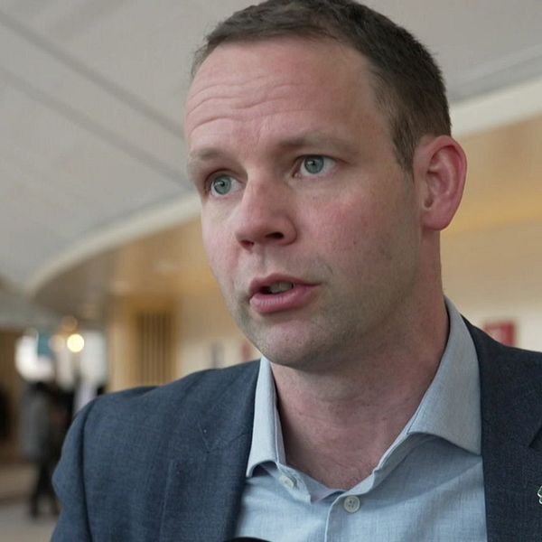 Reporter håller SVT-mikrofon i ett offentligt utrymme. Logotypen för Rapport syns.