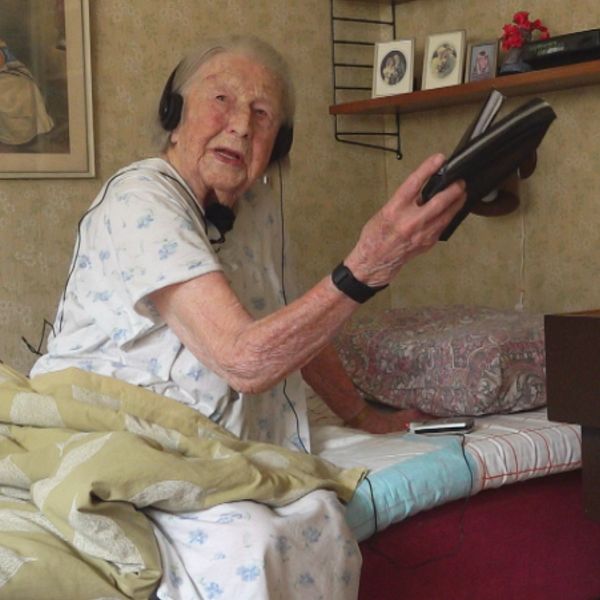 Anna-Lisa Malmgren, 108, sitter på sängkanten och håller i en plånbok i sitt sovrum.