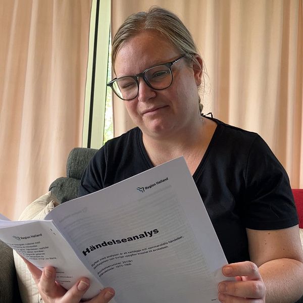 Rebecka Kristoffersson sitter i en soffa och läser Region Hallands utredning